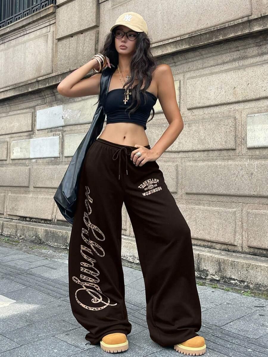 Woman wearing HUSTLE801 brown cotton Swagger pants with white graphic text, casual streetwear style
