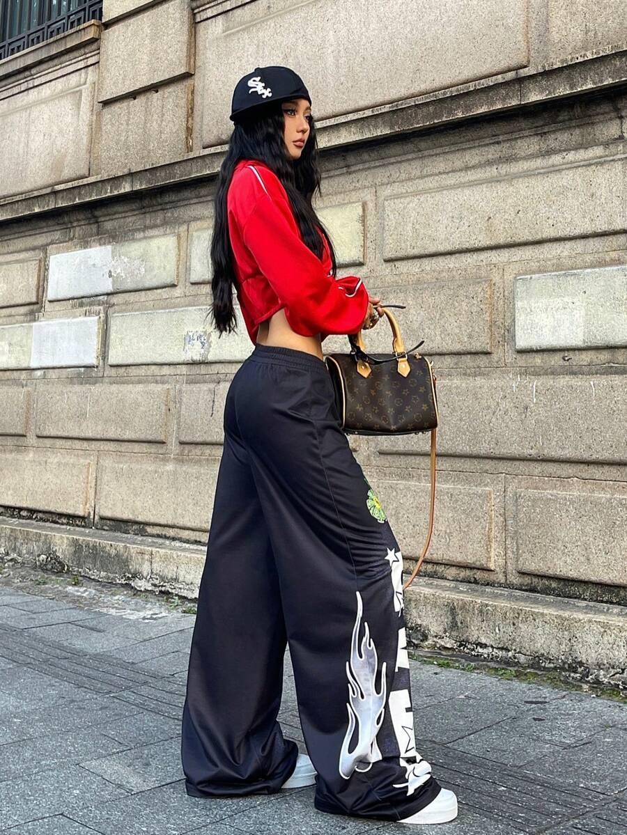 Woman in black cotton HUSTLE801 That Girl baggy pants with white flames, red crop top, street style