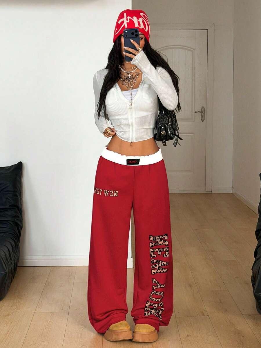 Red cotton New York baggy sweatpants with leopard print patches, worn with a white zip-up top
