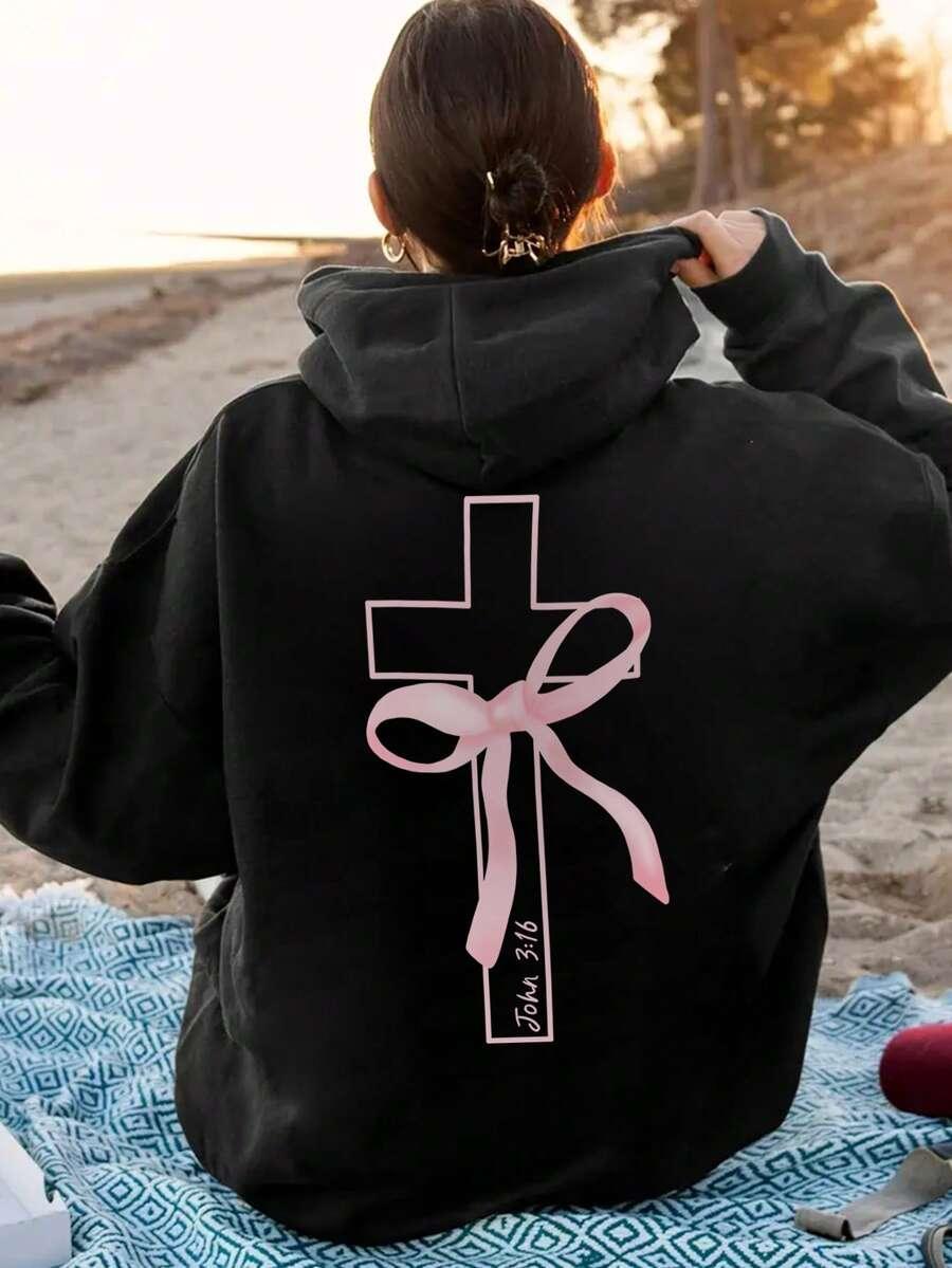 Black cotton hoodie with a pink cross and ribbon graphic, John 3:16, worn on the beach, HUSTLE801.