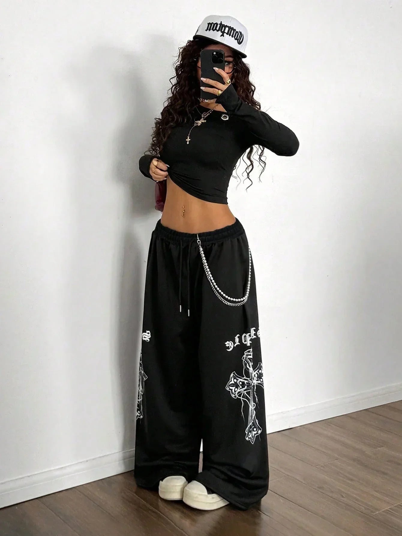 Woman wearing black cotton HUSTLE801 Crosswide Baggy Pants with white cross graphics and chain detail