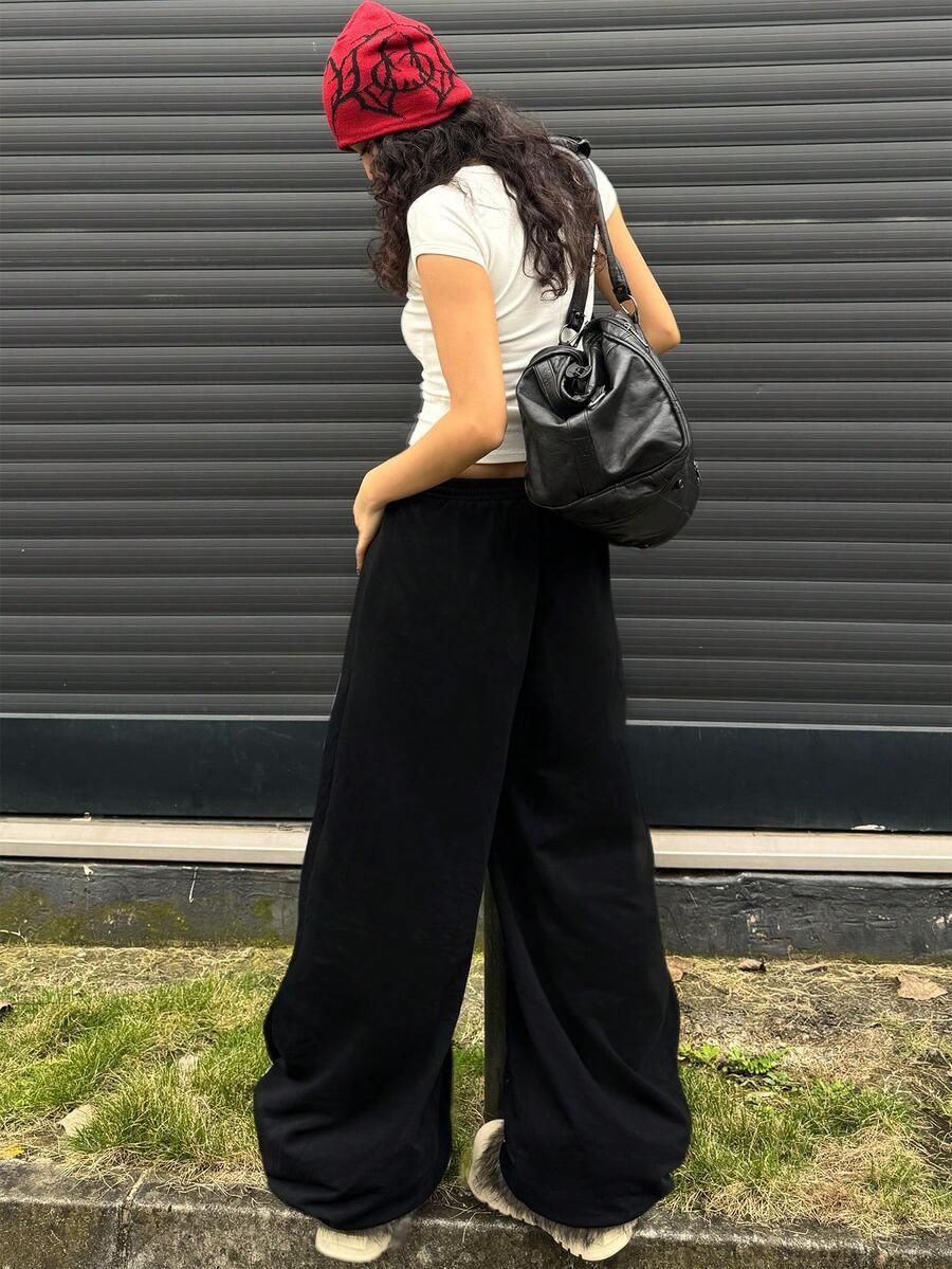 That Girl beanie in red knit, black cotton wide-leg pants, and black faux leather bag