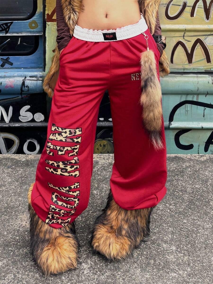 Red cotton HUSTLE801 HELLGIRL sweatpants with leopard print lettering, worn with faux fur accessories.