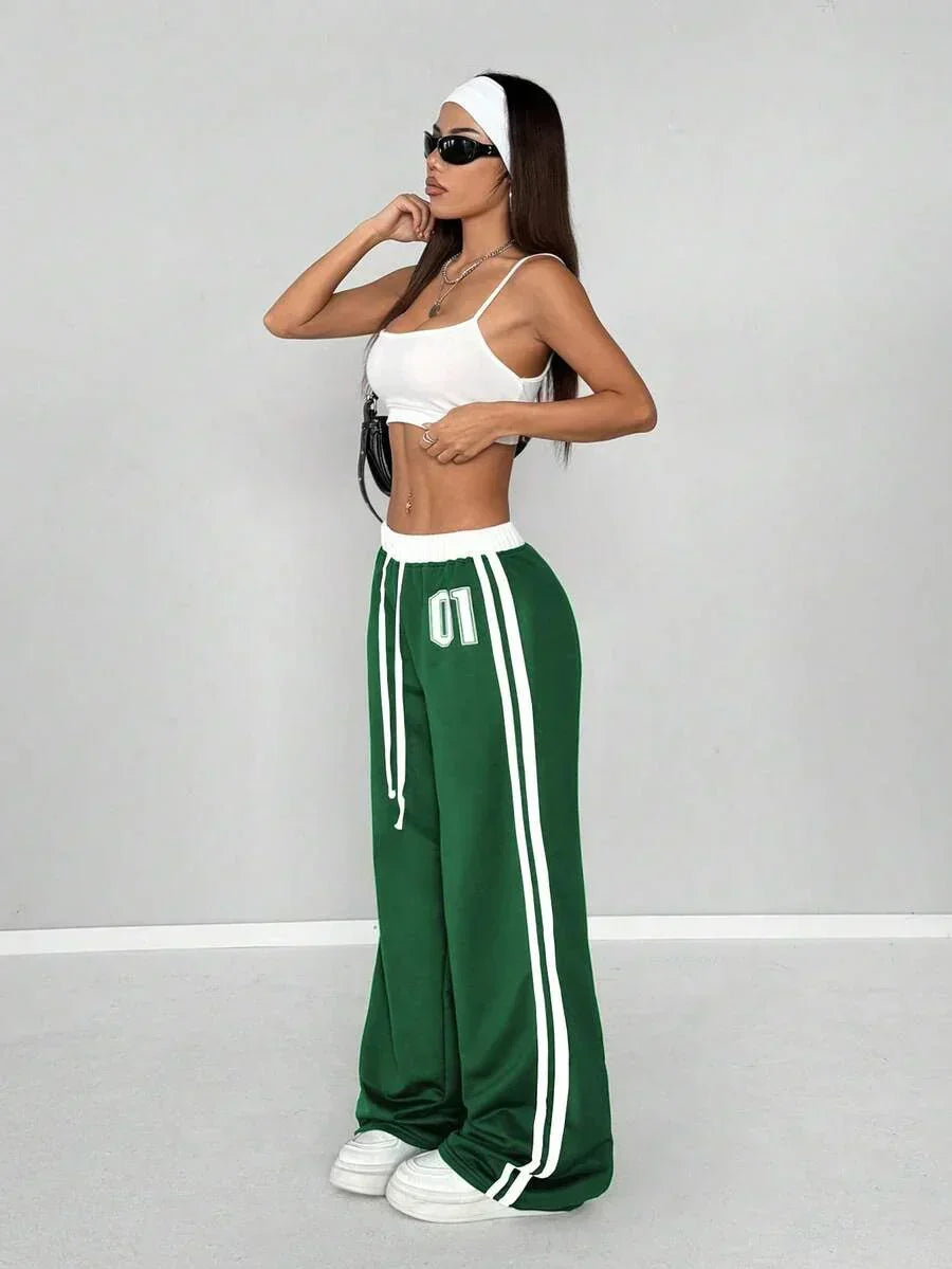 Woman modeling green cotton HUSTLE801 01 Baggy Sweatpants with white stripes and a white crop top